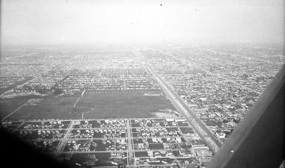 A vast aerial view of a dense, sprawling city grid stretching endlessly toward a hazy horizon.