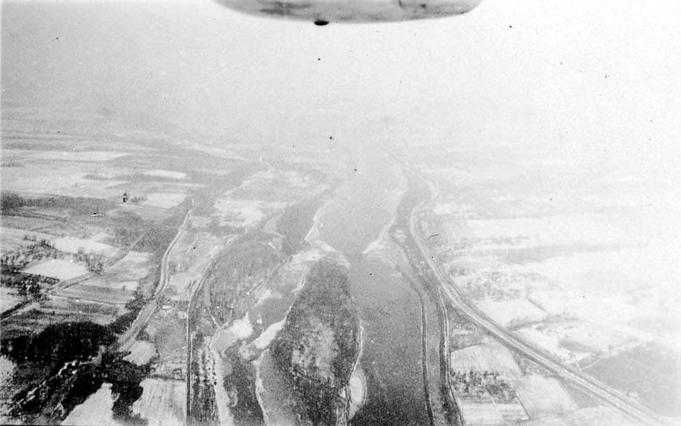A high-altitude aerial view looking down at a large river delta surrounded by snow-covered agricultural fields.