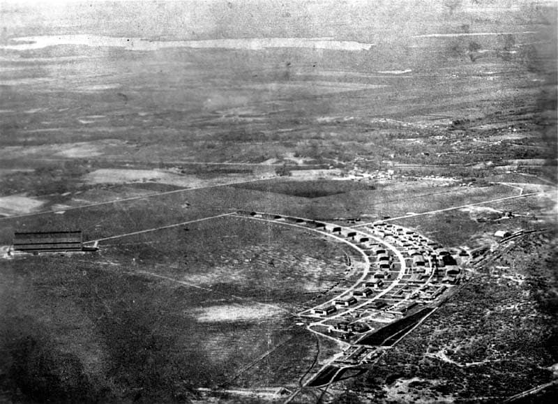 A sweeping aerial view of Brooks Field showcasing its iconic, semi-circular layout of aircraft hangars and support buildings.