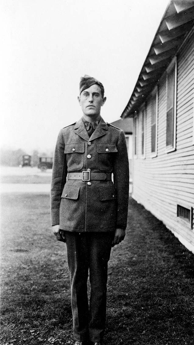 A full-length portrait of Donald A. Hall Sr. in a crisp Army Air Corps cadet dress uniform, standing outside a wooden barracks building at Brooks Field.