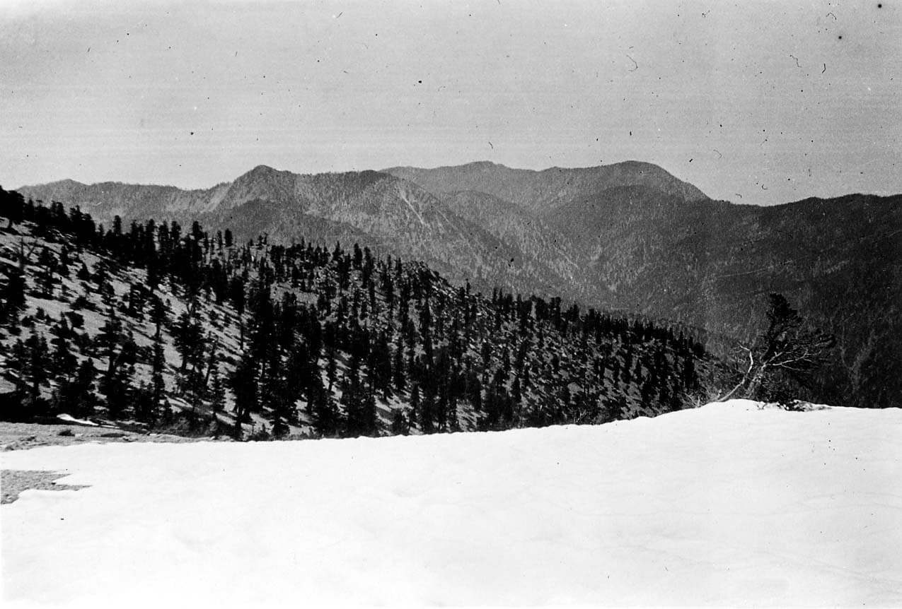 Low-hanging clouds settling into a deep mountain valley with show framing the cold ground.