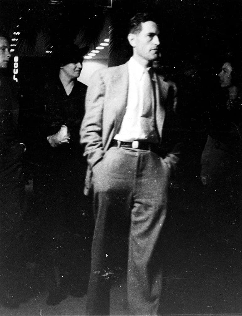 Candid photograph of Donald A. Hall Sr. in a light suit and tie walking through an indoor gathering.