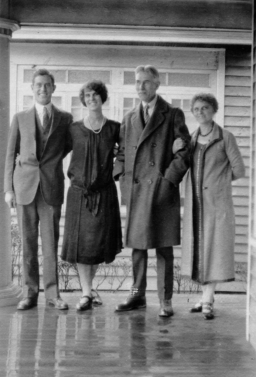 A family portrait of four people standing on a porch: Donald Hall, Alice Hall Smith, Harland Hall, and Louis Hall.