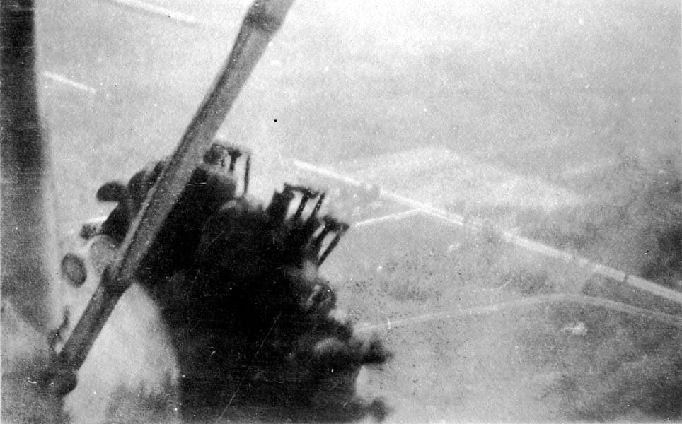 An incredibly close, hazy air-to-air view focusing on the spinning propeller, exposed cylinders, and exhaust manifolds of a Ford Tri-Motor radial engine.