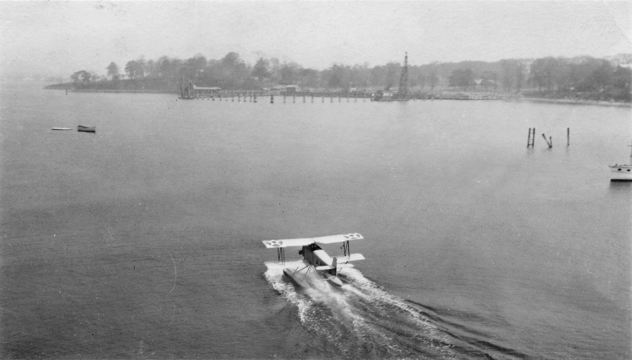 A seaplane or hydroplane creating a spray of water as it prepares for takeoff on a calm harbor or bay.