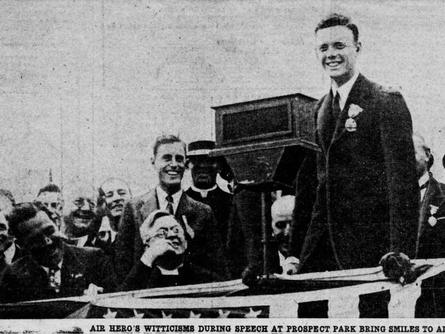 A newspaper clipping showing Charles Lindbergh smiling and speaking at a podium in Prospect Park, Brooklyn.