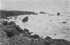 A vintage print of a secluded, rugged rocky ocean cove with dark rock formations and sea stacks rising from calm waters.