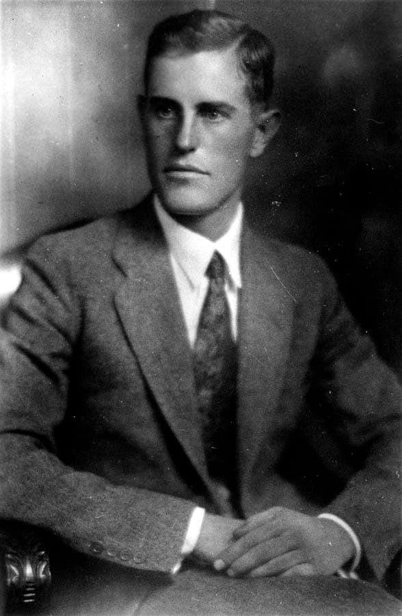 Three-quarter seated studio portrait of Donald A. Hall Sr. in tweed suit with hands clasped.