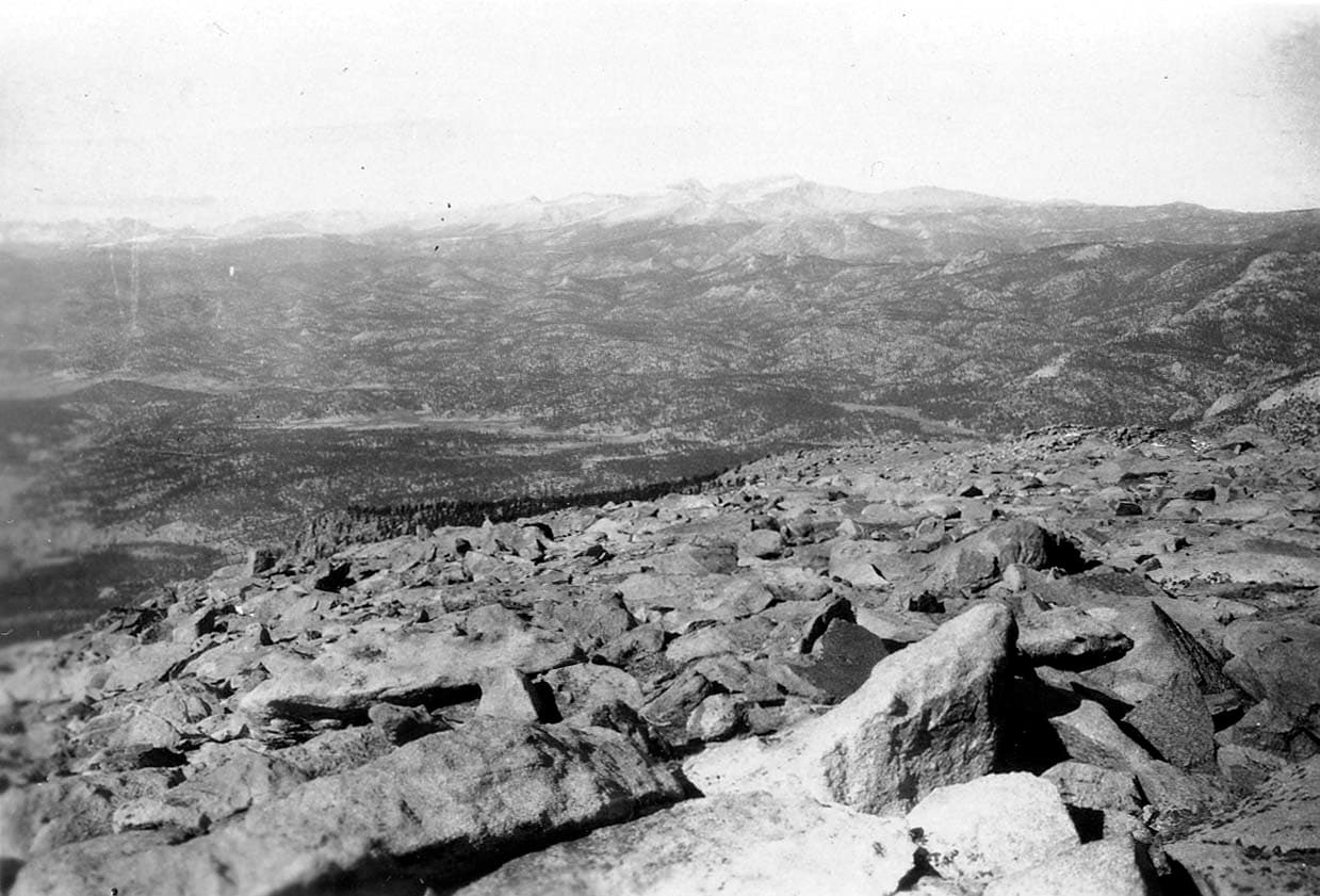 Uneven, rocky terrain sloping upwards toward a mountain crest in the distance well above the tree line.