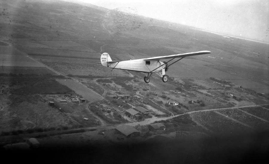 An air-to-air photograph showing the fully completed Spirit of St. Louis banking away over the California landscape.