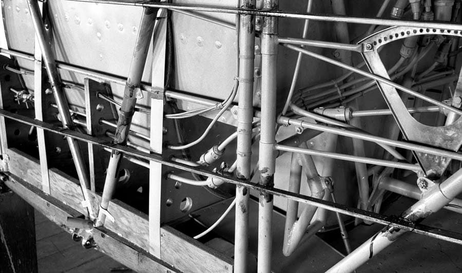 A close-up detailed view of the custom fuel lines, connections, and valves routing around the main fuel tank of the Spirit of St. Louis.