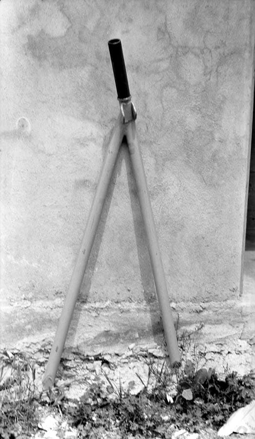 Another standalone view of the V-shaped chromoly steel landing gear axle for the Spirit of St. Louis, resting against an exterior wall.