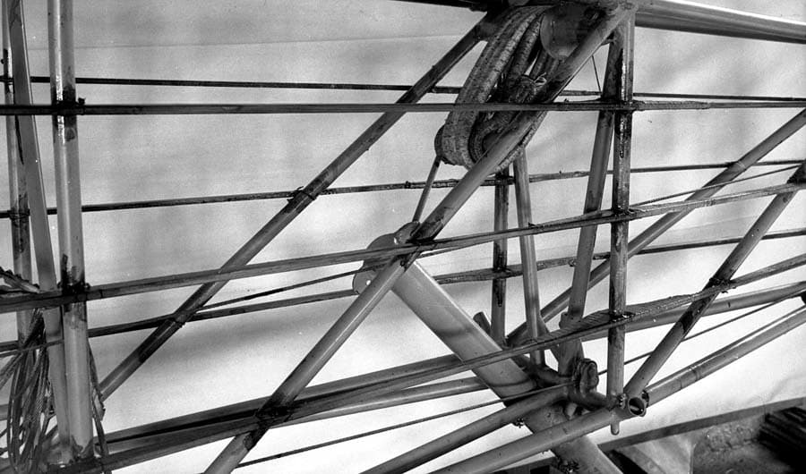A detailed view of the tubular steel tail section of the Spirit of St. Louis, focusing on the complex wrapping of the bungee cord shock absorbers.