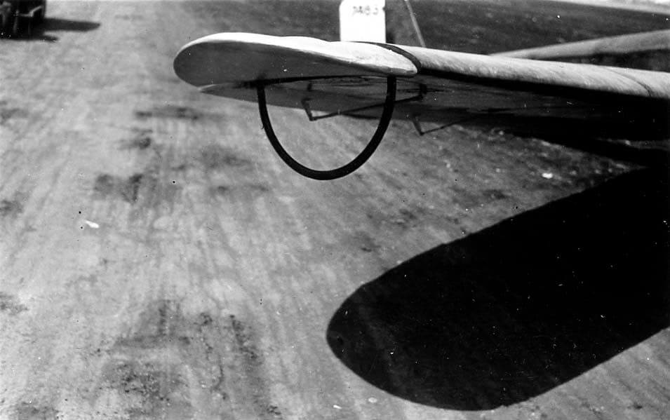 A close-up detail shot of the wingtip of the Spirit of St. Louis, showing a specialized, curved metal handling bar attached beneath the fabric surface.