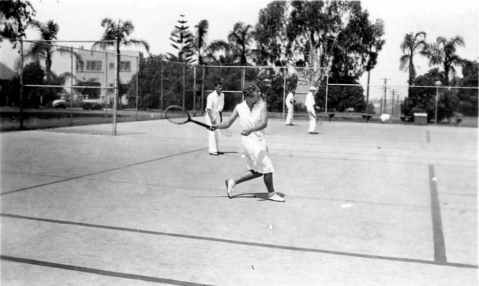 Two men and two women playing a mixed doubles tennis match on an outdoor court.