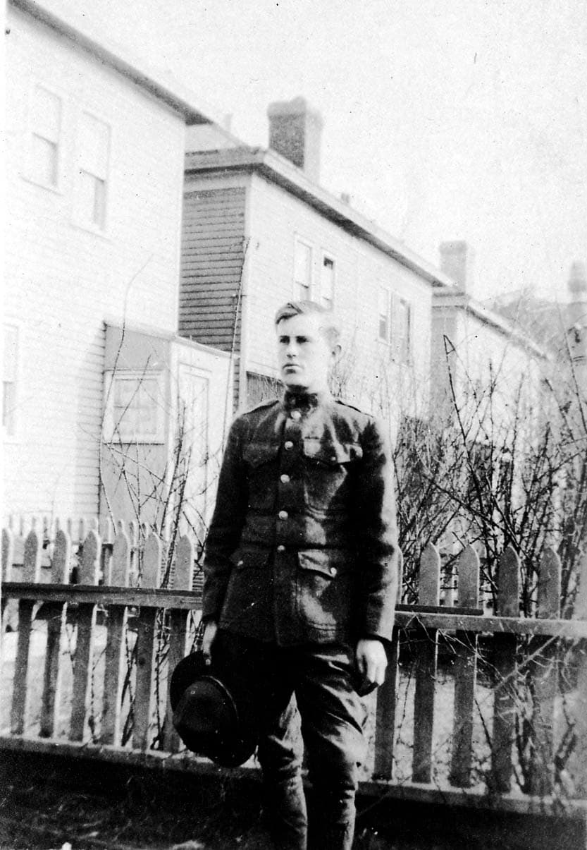 Young Donald A. Hall in U.S. Army World War I uniform holding service cap outside Brooklyn home.