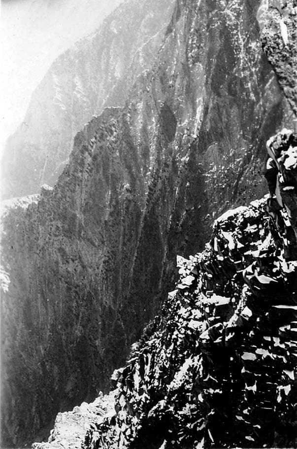 A steep, rocky mountain cliff face bathed in natural sunlight.