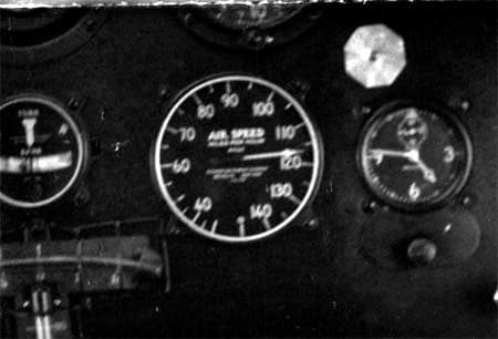 Macro photograph of cockpit instrument cluster during high-speed test run showing airspeed indicator needle at 120 mph.