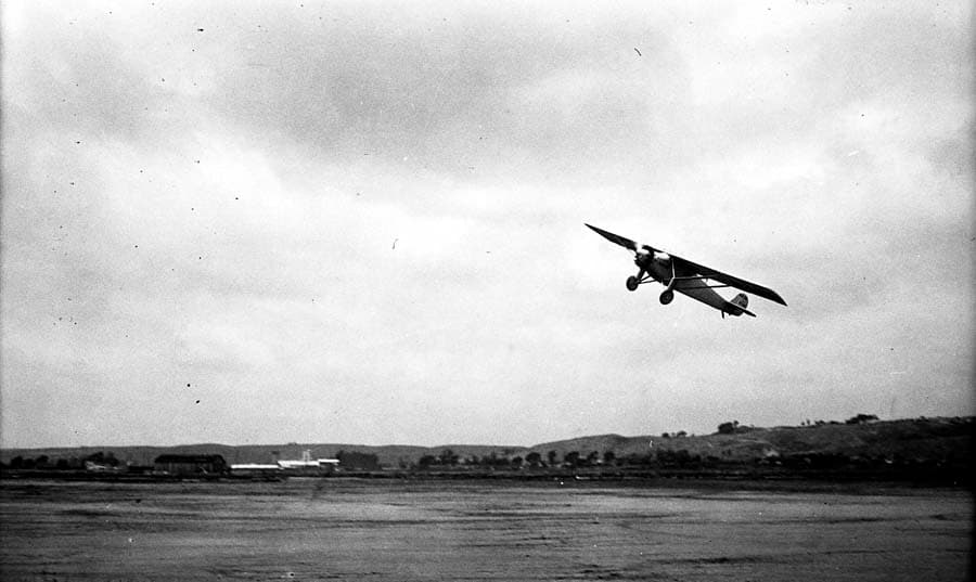Low-angle action photograph of the Spirit of St. Louis climbing into the overcast sky over Dutch Flats.