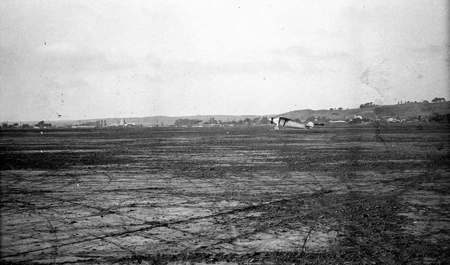 Long-distance airfield photograph of the Spirit of St. Louis rolling out across Dutch Flats at touchdown.