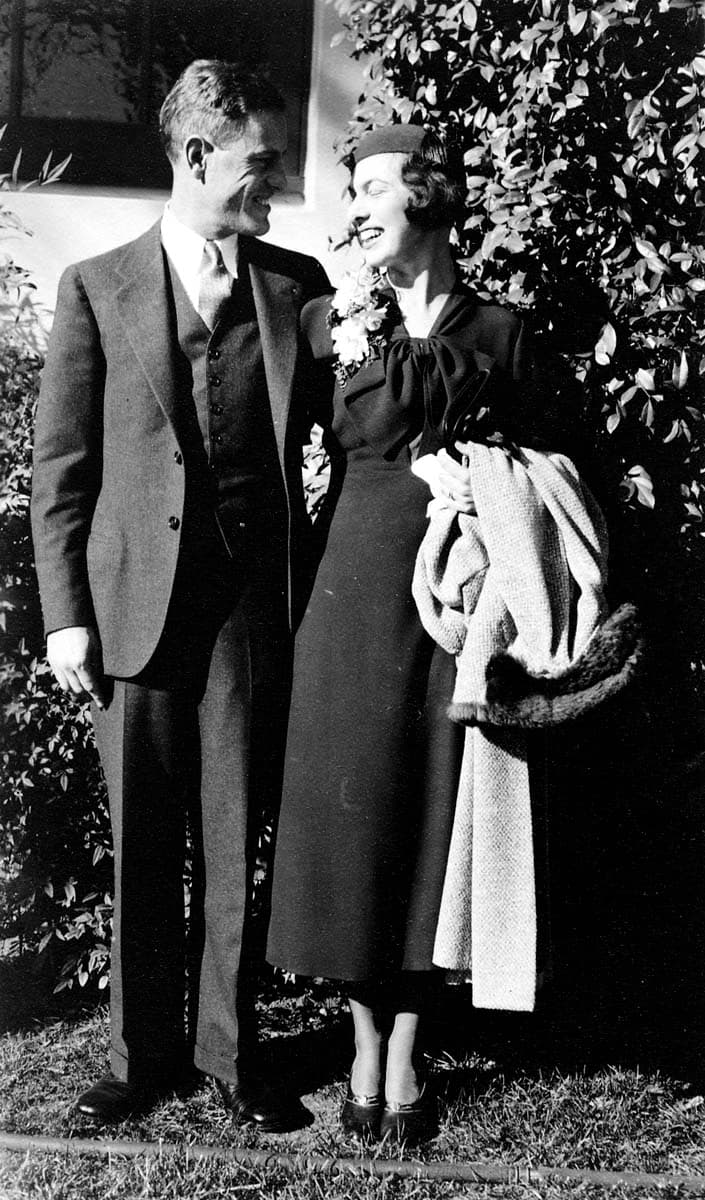 Donald A. Hall Sr. in a tailored three-piece suit smiling at his wife Elisabeth in a garden setting.