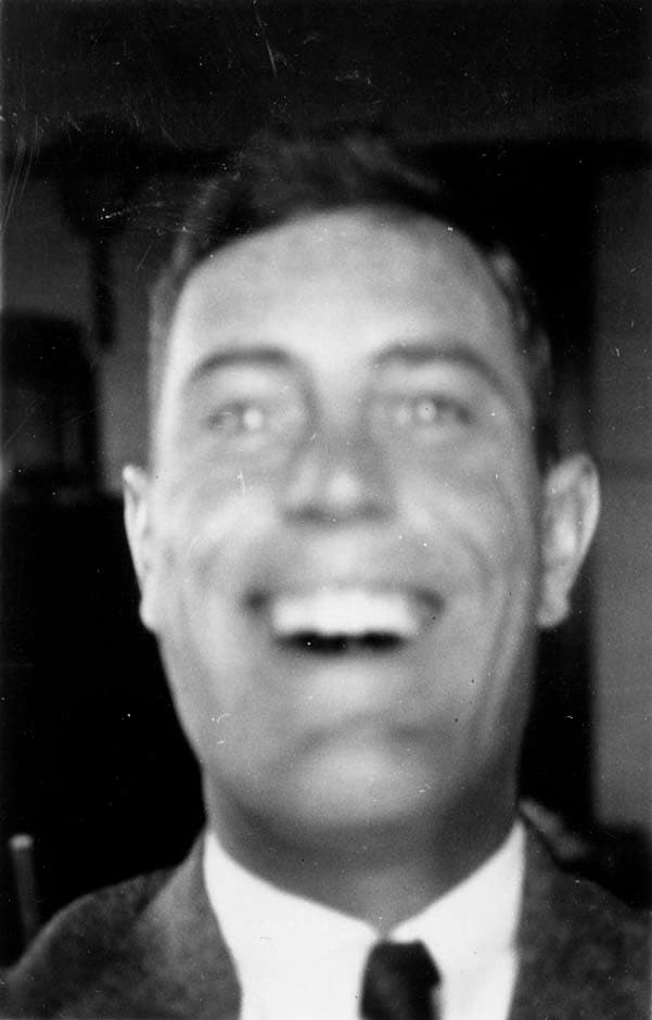 A candid close-up self-portrait of Donald A. Hall Sr. laughing broadly while dressed in a three-piece suit and necktie.