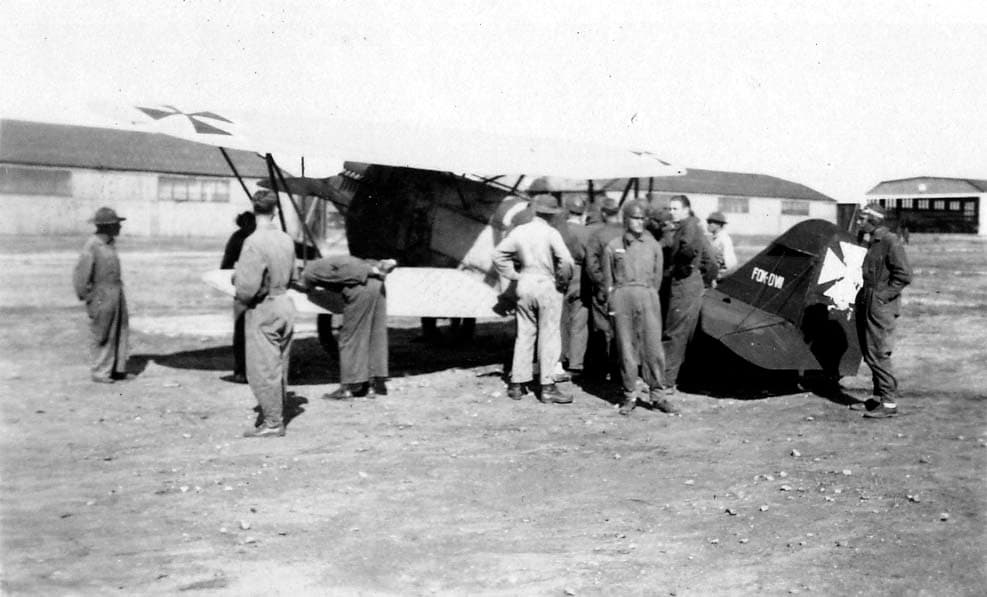 Army Air Corps flight cadets, including Donald A. Hall Sr. wearing a flight cap, examining a captured German WWI biplane with Iron Cross markings at Brooks Field.