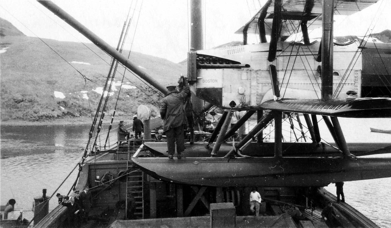 Ground crew and naval officers servicing the Liberty engine and propeller of the Douglas World Cruiser Boston moored against a support ship.
