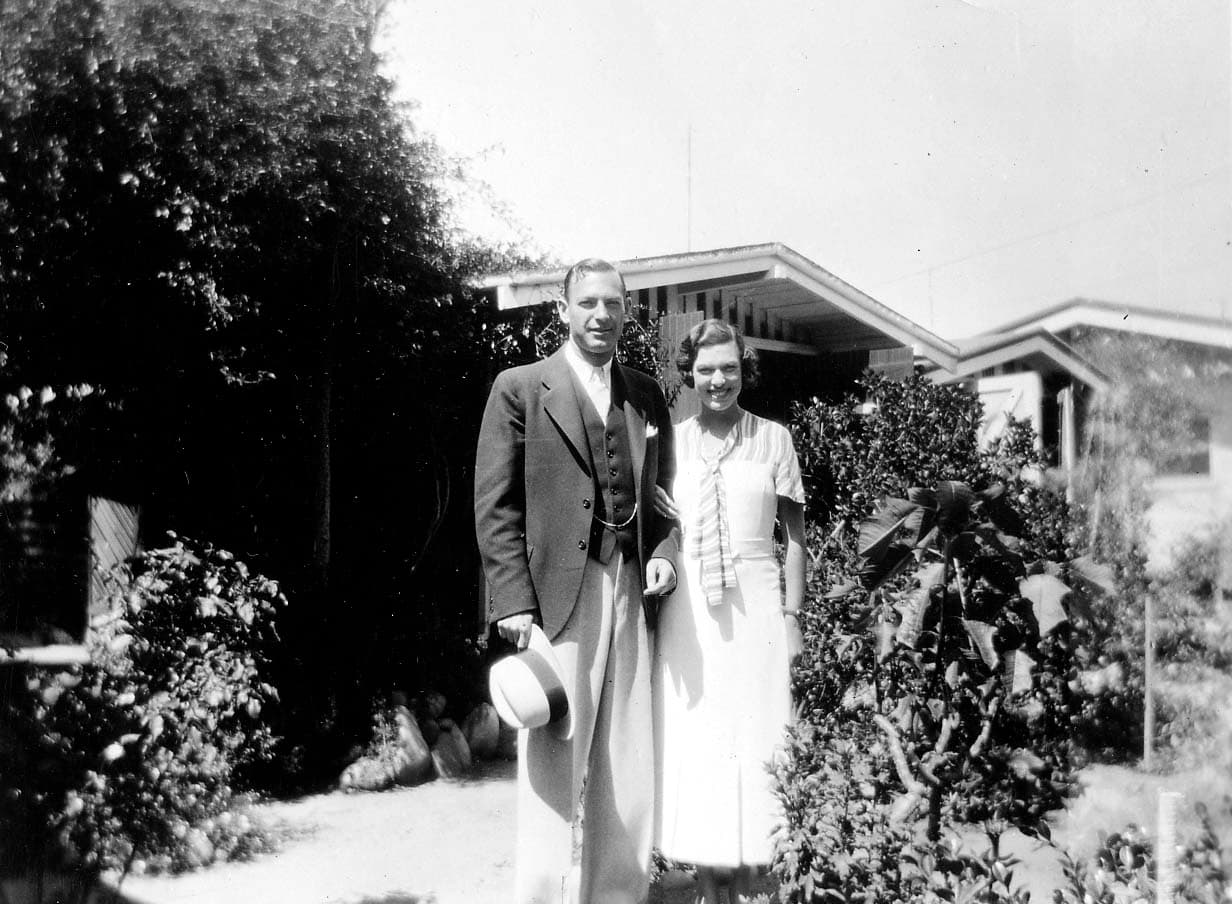 Elisabeth Betty Walker smiling in a summer dress alongside her brother Omar Walker in a three-piece suit holding a hat in a sunny garden.