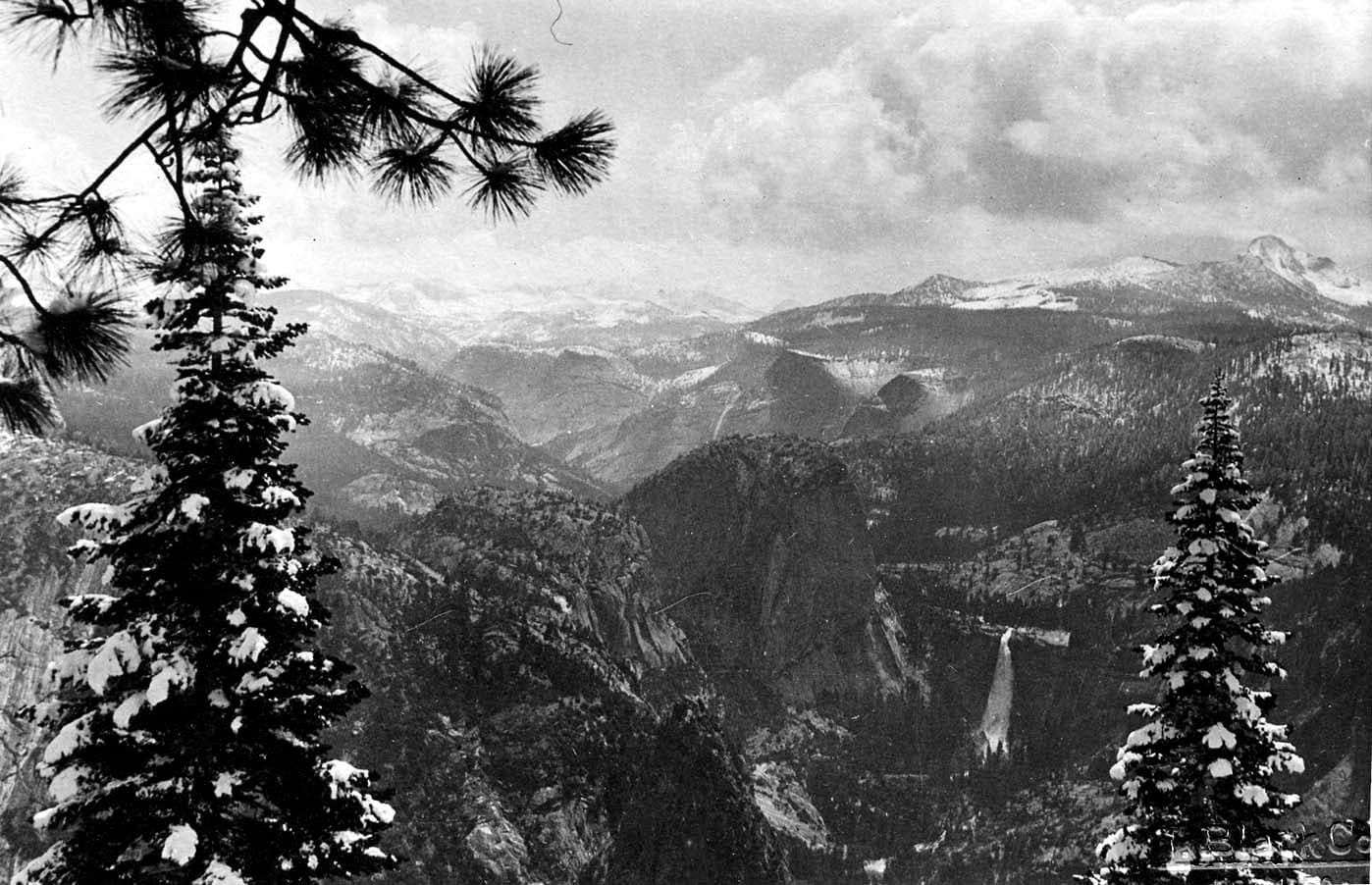 A sweeping high-altitude winter panorama from Glacier Point across snow-covered pines toward Liberty Cap and distant Nevada Fall.