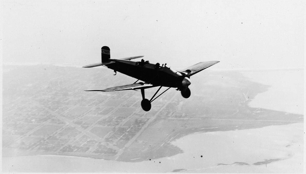 An air-to-air high-angle view of the Hall X-1 prototype X7621 banking high above the urban grid of San Diego and coastal bay.