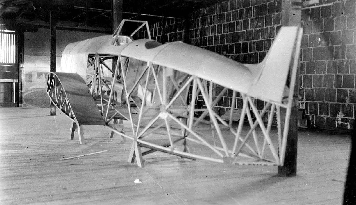 The uncovered welded tubular steel fuselage frame and turtledeck of the Hall X-1 under construction inside a wooden workshop.