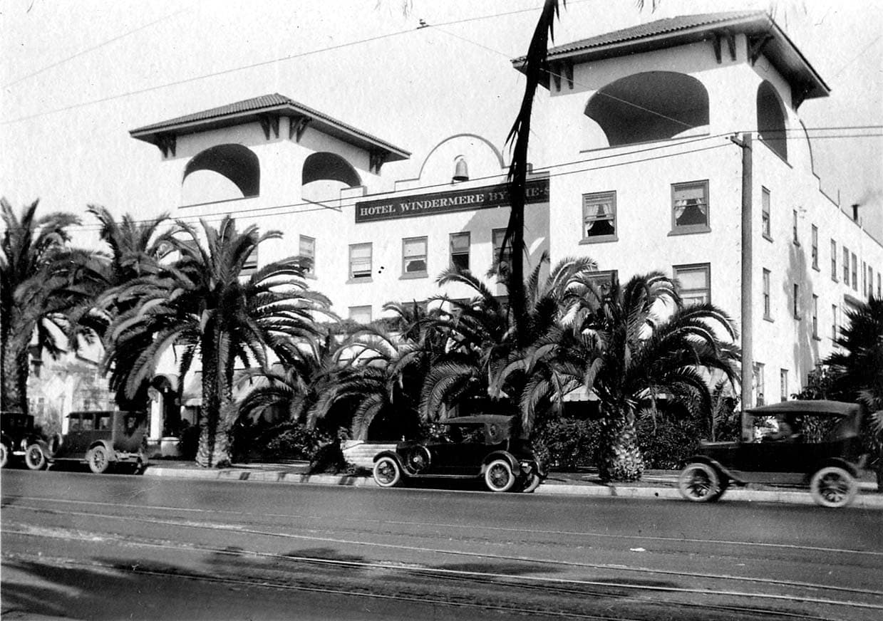 The Spanish Colonial Revival facade of Hotel Windermere by the Sea on Ocean Avenue in Santa Monica with palm trees and vintage cars.