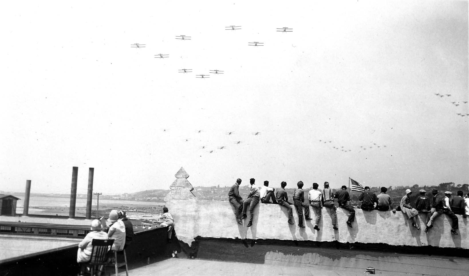 Rare photos by the Chief Engineer from the roof of Ryan Airlines, in San Diego, California with the employees. Biplanes visible in the distance against the clouds.