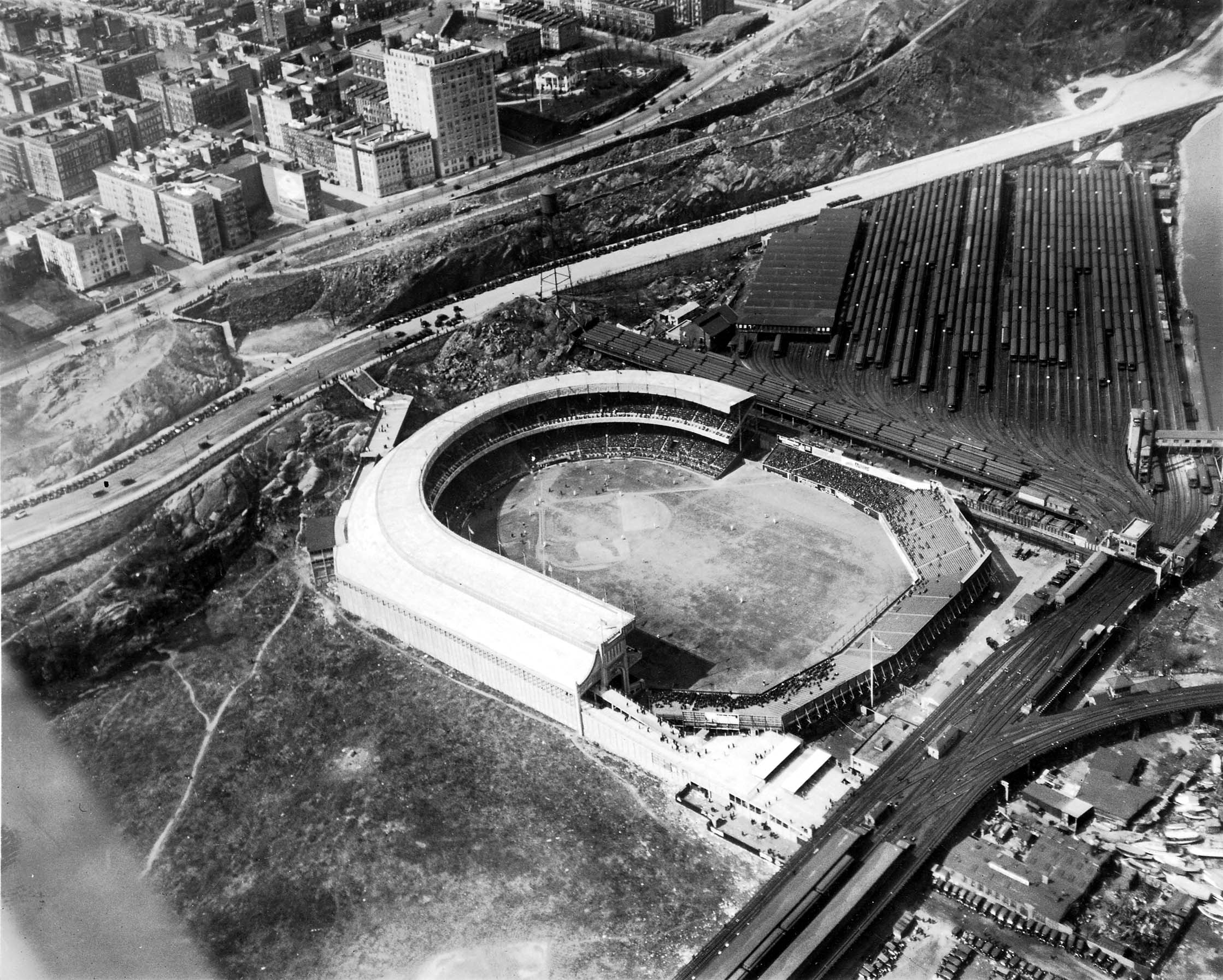 An authentic aerial view looking down from an aircraft at the Polo Grounds stadium, Coogan's Bluff, and the IRT elevated train yard beside the Harlem River.
