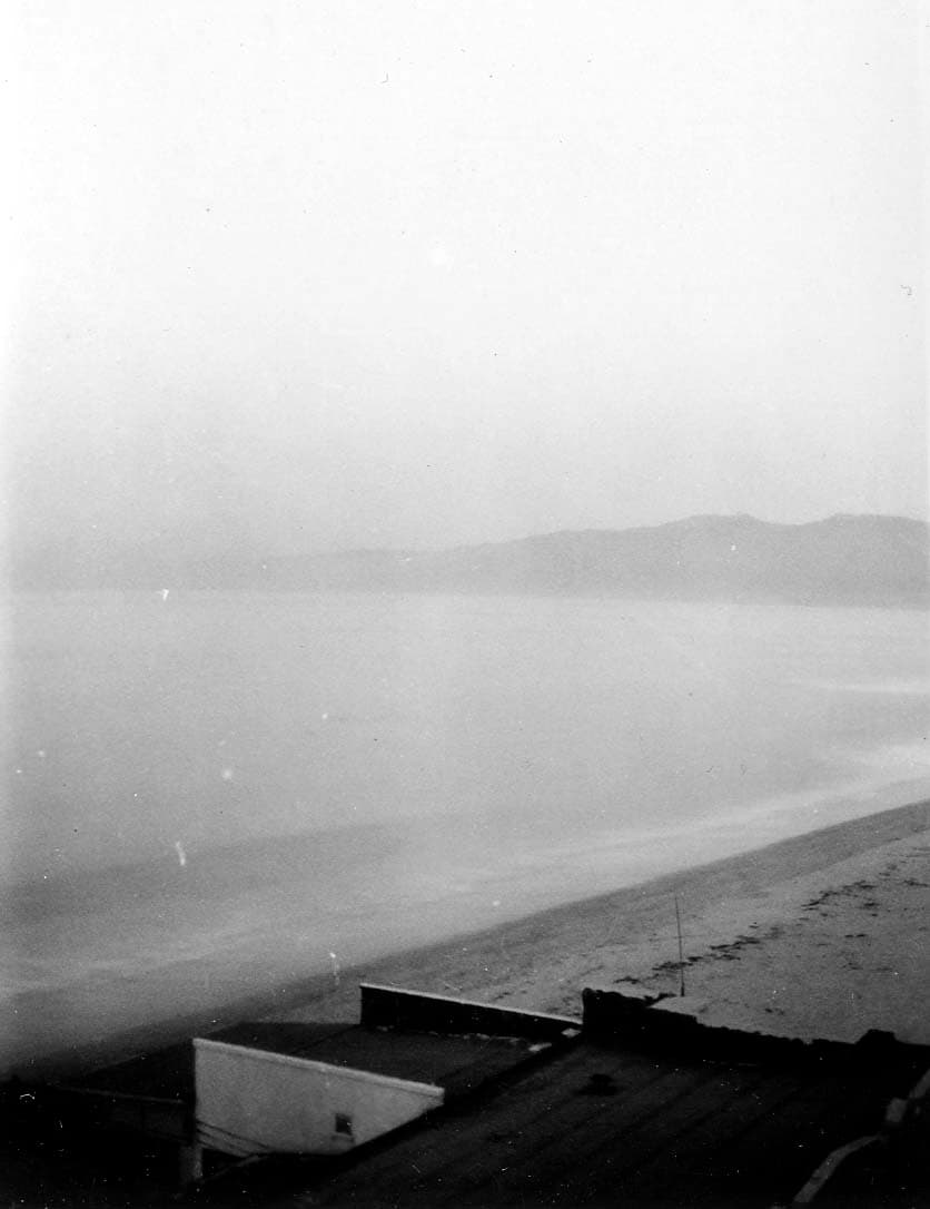 Dense marine layer fog and soft atmospheric haze obscuring the calm waters of Santa Monica Bay and distant coastal mountain ridges.