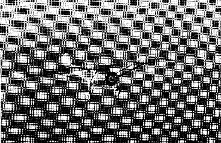 Halftone photographic print reproduction of the Ryan NYP Spirit of St. Louis cruising in flight over coastal terrain.