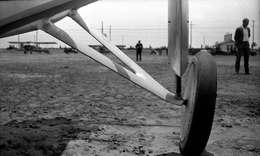 A rear-angle view looking past the aerodynamic landing gear fairings and wheels of the Spirit of St. Louis parked at Dutch Flats.