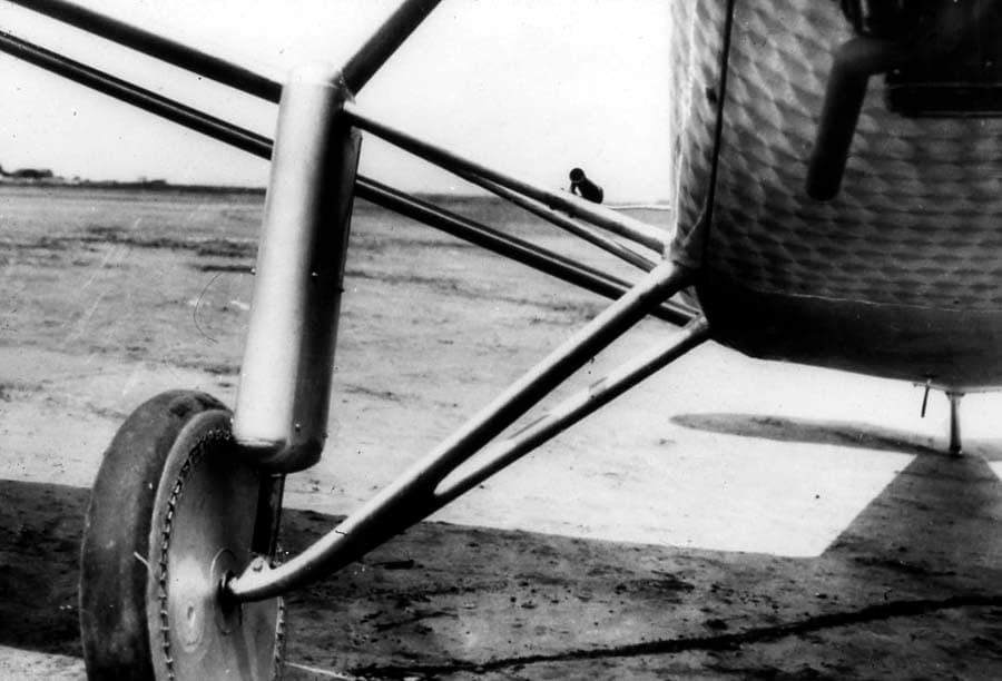 Close-up photograph of the right landing gear assembly showing streamlined shock-strut fairing and fabric-doped wire wheel.