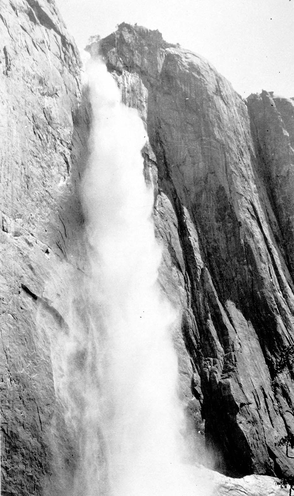 An intense close-up vertical perspective of Upper Yosemite Fall roaring down the polished granite cliff face toward the trail base.