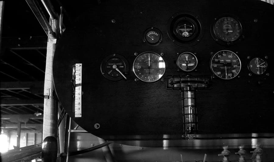 Close-up view of the black oval instrument panel showing compass, airspeed, tachometer, and calibrated starter lever.