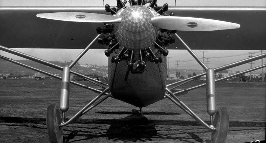 Head-on close-up photograph of the Spirit of St. Louis nose showing damascened cowl, spinner, engine, and gear struts.
