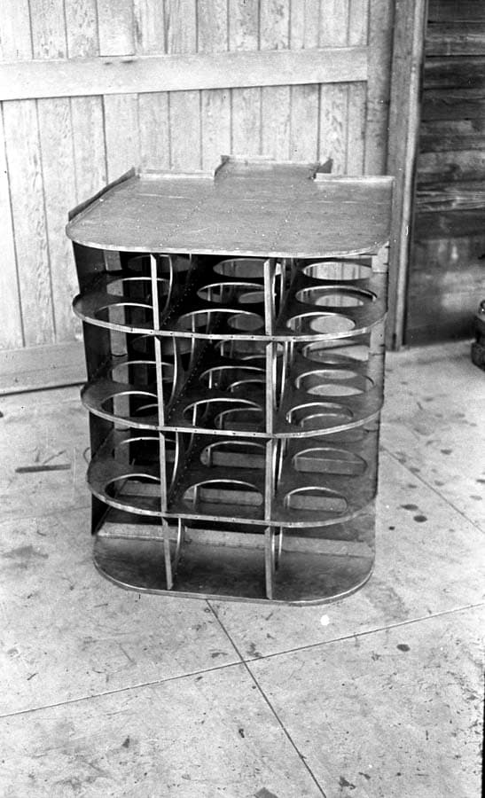 Frontal view of internal fuel tank baffle grid resting on wooden sawhorses outside the workshop door.