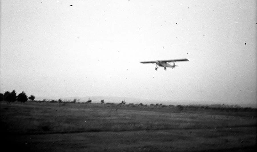 Airborne photograph of the Spirit of St. Louis banking low over the terrain during Camp Kearny flight trials.