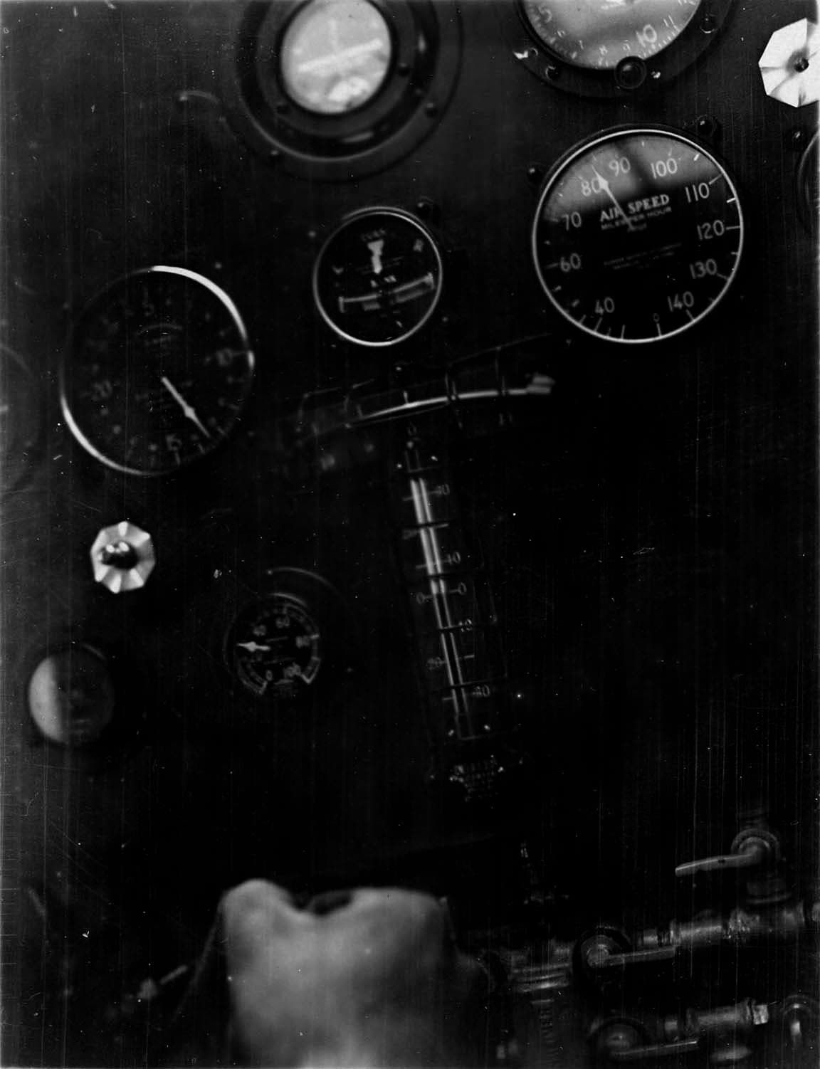 Close-up of cockpit instruments in flight showing airspeed at 98 mph and Lindbergh's gloved hand holding the stick.