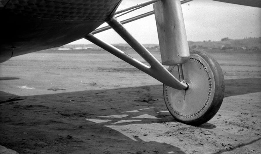 Macro ground-level photograph of the right landing wheel showing fabric disc stitching and streamlined shock strut boot.