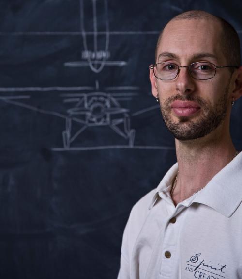 Photo of Nova Hall with a drawling of the Spirit of St. Louis behind him on a chalk board.