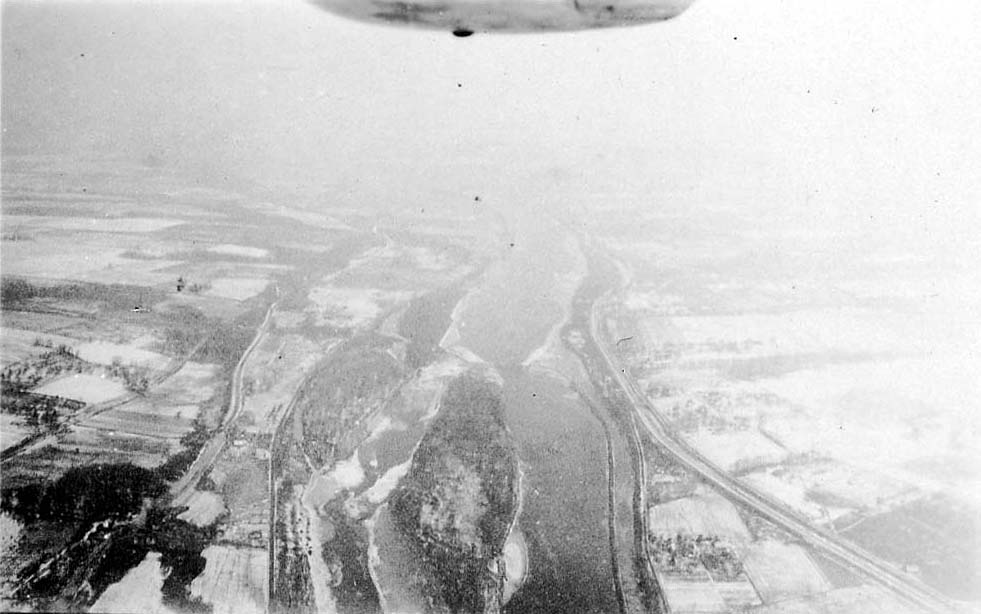A high-altitude aerial view looking down at a large river delta surrounded by snow-covered agricultural fields.