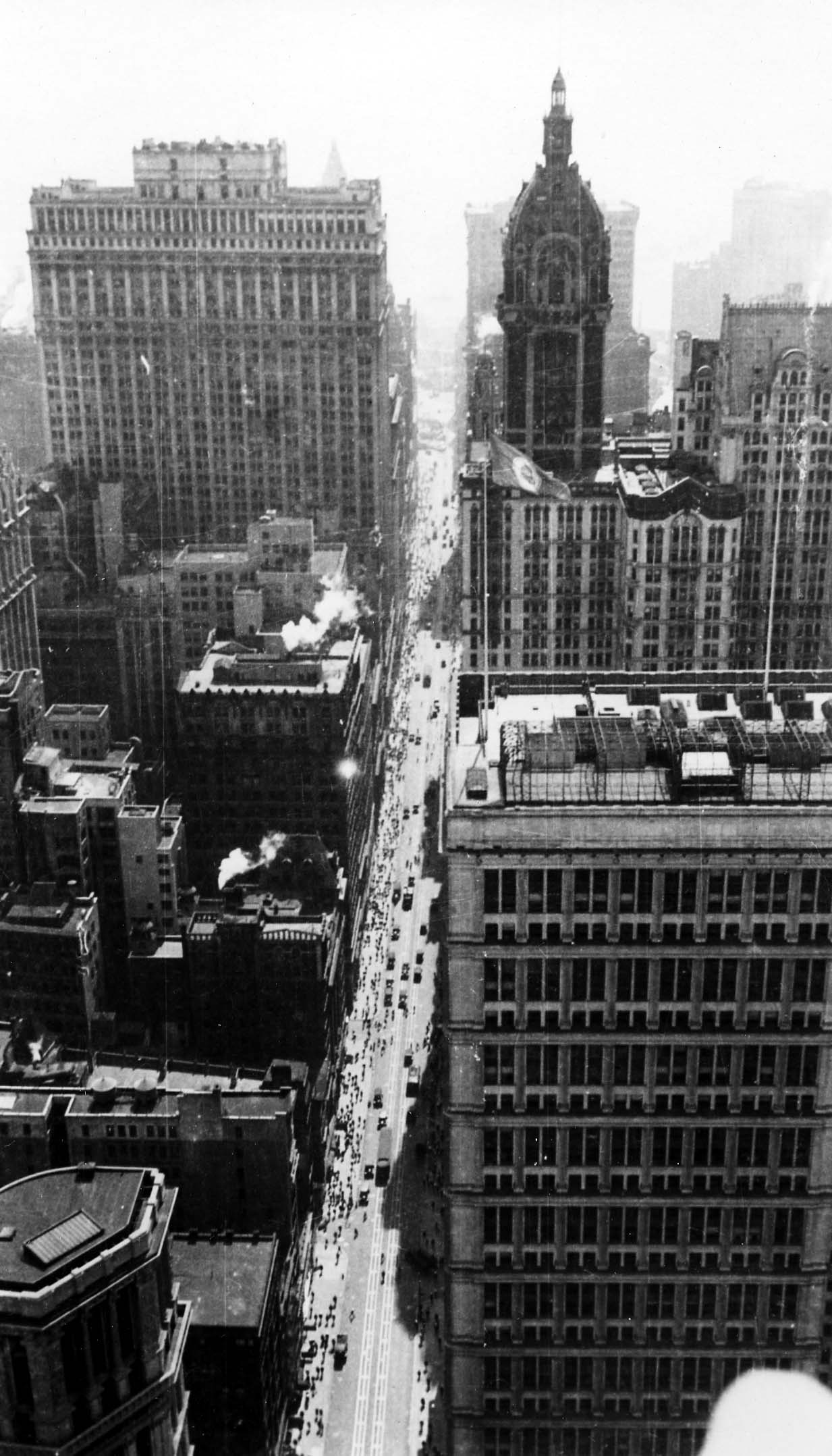 A steep downward view overlooking the Broadway canyon, the tiered facade of the St. Paul Building, and crowds lining the street during Lindbergh celebration week.