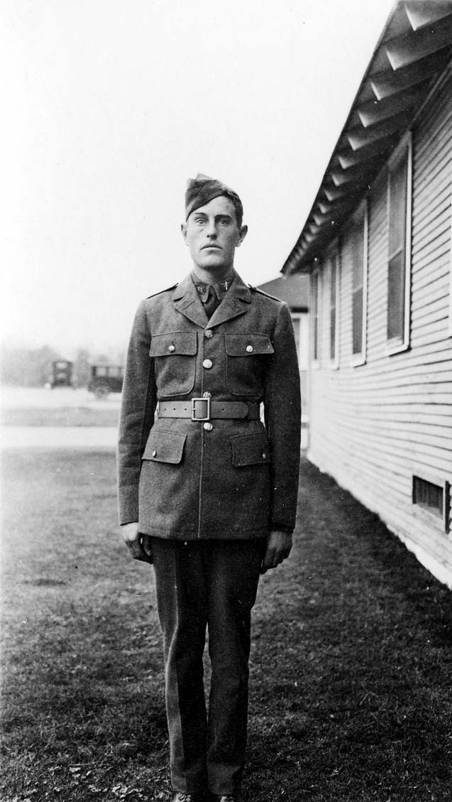 A full-length portrait of Donald A. Hall Sr. in a crisp Army Air Corps cadet dress uniform, standing outside a wooden barracks building at Brooks Field.